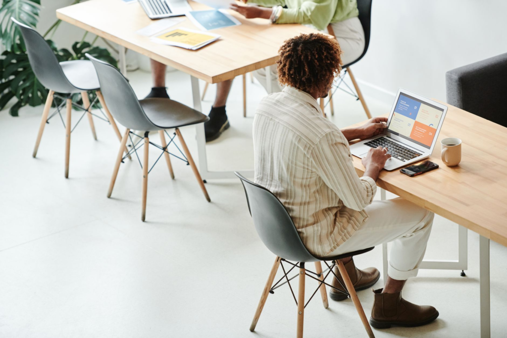 A business professional standing in an open office, looking ahead with a focused and confident expression.