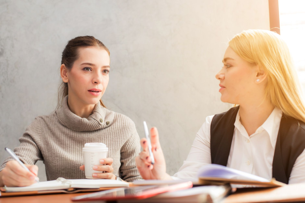 A business coach in a one-on-one conversation with a leader in a modern office setting.